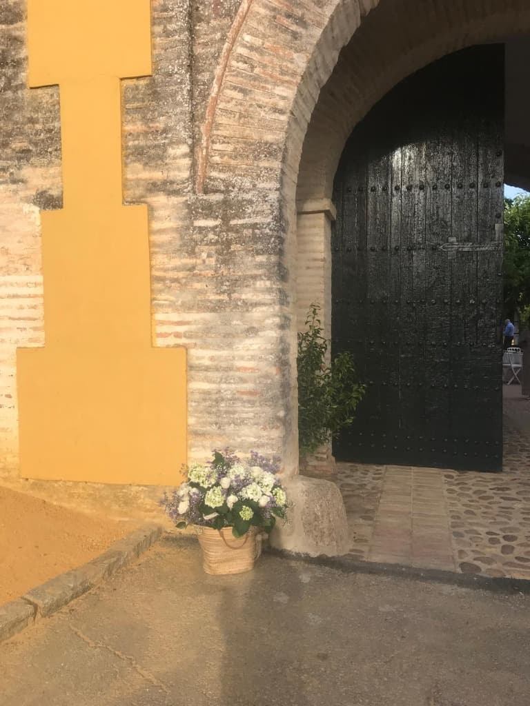 Cesta Flores Porton Hacienda Cesta de mimbre con flores y decoración floral al lado del portón de madera negro de la hacienda
