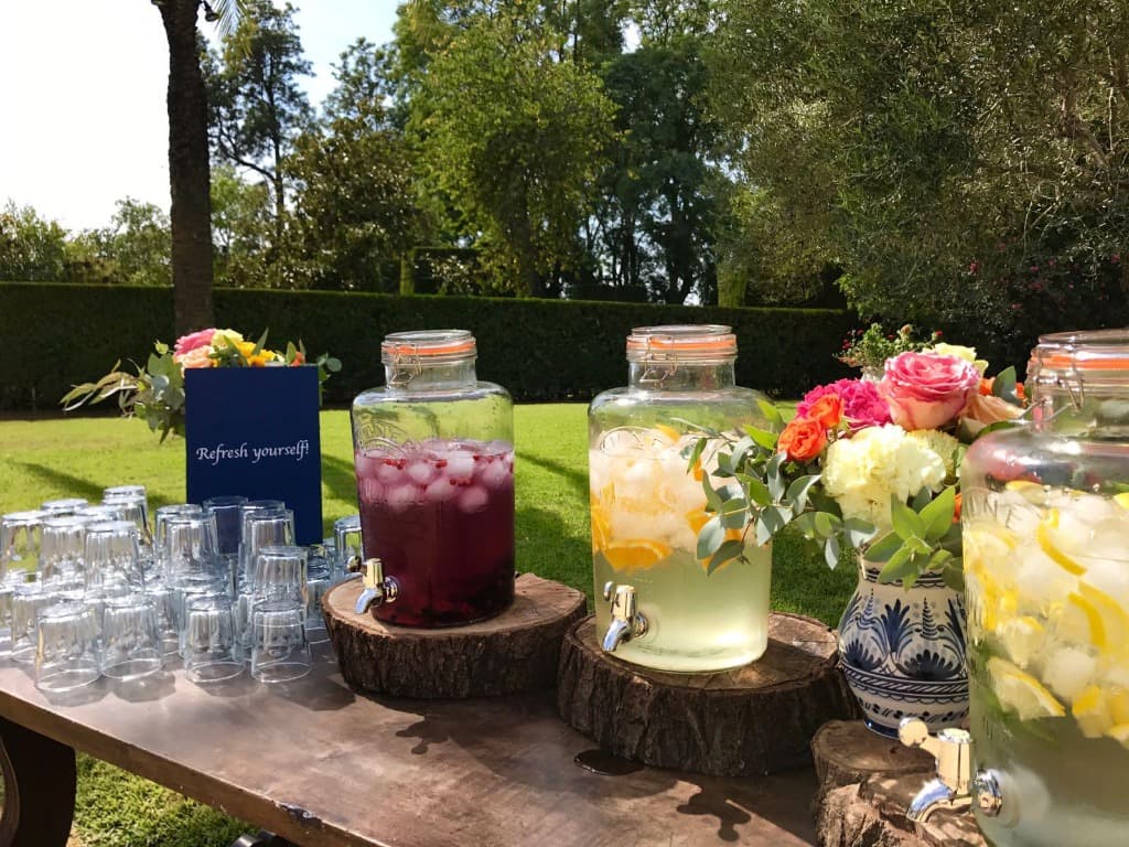 Mesa Bebidas Boda Rustica Mesa de bebidas refrescantes y limonada con dispensadores de cristal sobre rodajas de madera